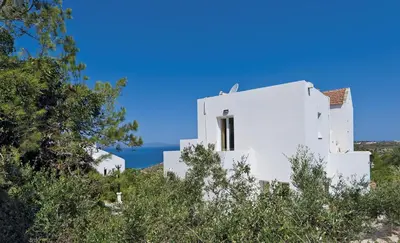 a white house on a hill with the ocean in the background at Tersanas Village Apartments in Tersanas
