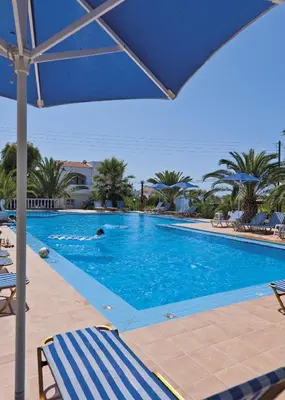 a person swimming in a swimming pool with an umbrella at Tersanas Village Apartments in Tersanas