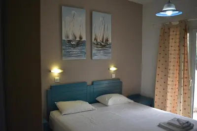 a bedroom with a blue bed with three pictures on the wall at Tersanas Village Apartments in Tersanas