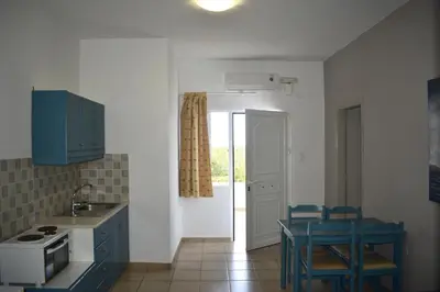 a kitchen with blue cabinets and a table and chairs at Tersanas Village Apartments in Tersanas