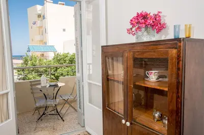 a room with a balcony with a table and a vase of flowers at The Romantic Beach House in Chania Town