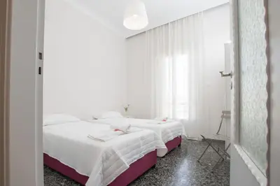 two beds in a room with white walls and a mirror at The Romantic Beach House in Chania Town
