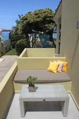 a bench with two pillows on a balcony with a table at Effi Apartments in Plataniás
