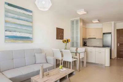a living room with a couch and a table and a kitchen at Resitour - Aphrodite Beachfront in Pírgos Psilonérou