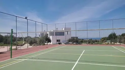 a tennis court with a building in the background at Villa Kounoupidiana in Kounoupidhianá