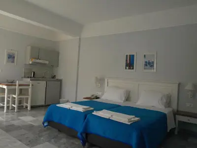 a bedroom with a blue bed and a kitchen at Santa Irene in Sougia