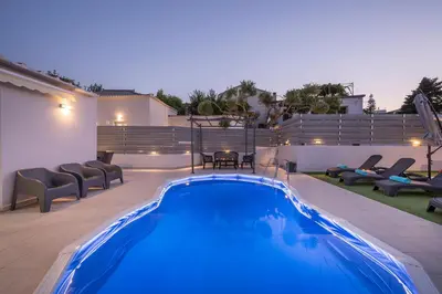 a swimming pool in a yard with chairs and a patio at b&m villas in Metókhion Sirilíou