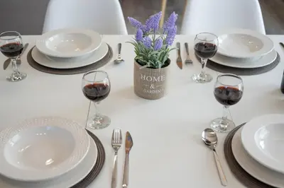 a table with glasses of wine and a vase of purple flowers at b&m villas in Metókhion Sirilíou