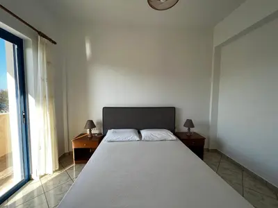 a bedroom with a large bed with two tables and a window at Grammeno Seaside Studios in Palaiochóra