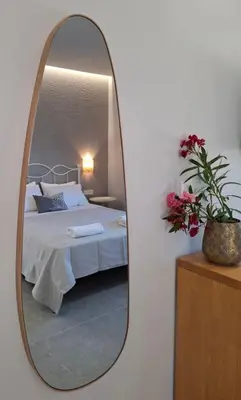 a mirror in a bedroom with a bed and flowers at Grammeno Seaside Studios in Palaiochóra