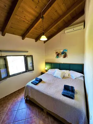 a bedroom with a bed with two blue towels on it at Villa Rosemari, Anatoli Apartment in Afráta