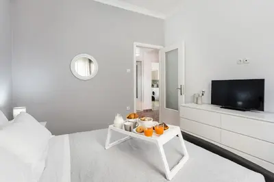 a white bedroom with a television and a table with oranges on it at Anemelia in Chania Town