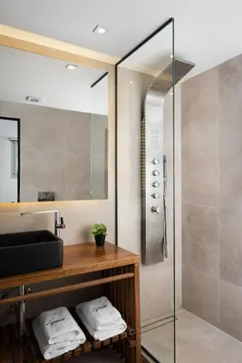 a bathroom with a shower and a sink with towels at Lignum Suites Chania in Chania Town