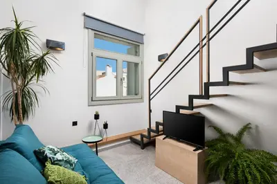 a living room with a blue couch and a staircase at Lignum Suites Chania in Chania Town