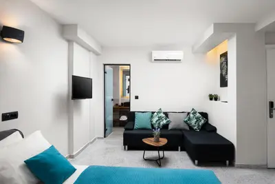 a living room with a black couch and blue pillows at Lignum Suites Chania in Chania Town