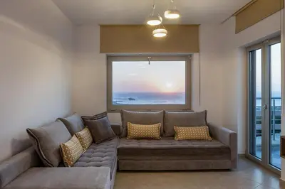 a living room with a couch and a large window at Magnolia Luxury Apartments in Falasarna