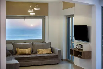 a living room with a couch and a large window at Magnolia Luxury Apartments in Falasarna