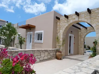 a villa with a stone wall and an archway at Azure Beach Villas in Kissamos