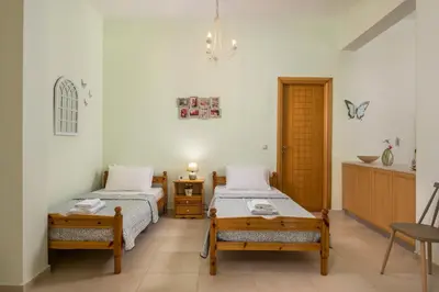 a bedroom with two beds and a table and a chair at OLIVE BREEZE in Kissamos