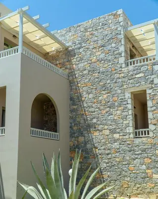 a building with a stone wall with windows at Erato Beach Hotel Adults Only by Smile Hotels in Plataniás