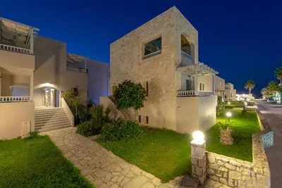 a large white house with a street at night at Erato Beach Hotel Adults Only by Smile Hotels in Plataniás