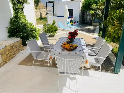 a table with chairs and a vase of flowers on it at The Green Home in Afráta
