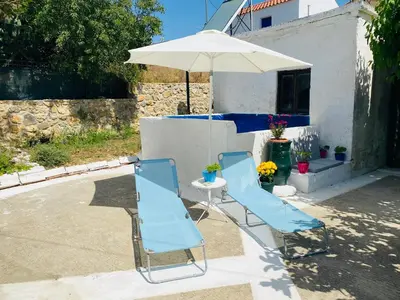 two blue chairs and an umbrella on a patio at The Green Home in Afráta