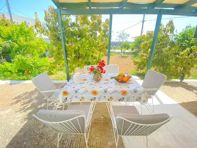 a table with chairs and a table with flowers on it at The Green Home in Afráta