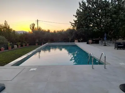 a swimming pool with a sunset in the background at Raphael Evangellos Villa in Gavalochori