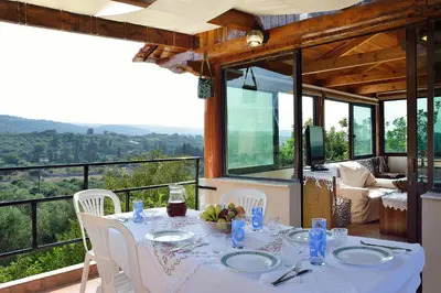 a white table with white chairs in a room with windows at Raphael Evangellos Villa in Gavalochori