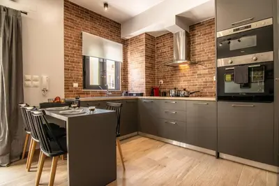 a kitchen with gray cabinets and a counter with chairs at MOS Luxury City Suites - The Loft in Chania Town