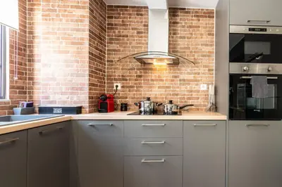 a kitchen with white cabinets and a brick wall at MOS Luxury City Suites - The Loft in Chania Town