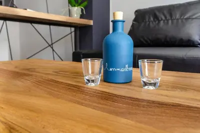 a blue bottle and two glasses on a wooden table at MOS Luxury City Suites - The Loft in Chania Town