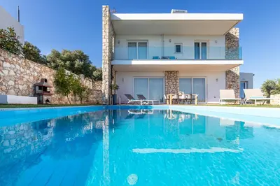 a villa with a swimming pool in front of a house at Villa PENELOPE in Galatás