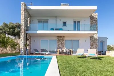 a villa with a swimming pool in front of a house at Villa PENELOPE in Galatás