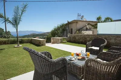 a table with wicker chairs sitting on a patio at Kamartsos Villa 3 in Áyios Yeóryios
