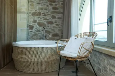 a bathroom with a bath tub and a chair at Kamartsos Villa 3 in Áyios Yeóryios