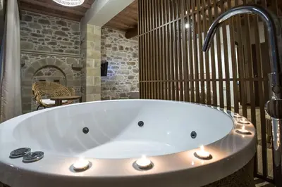 a large bath tub in a bathroom with a stone wall at Kamartsos Villa 3 in Áyios Yeóryios