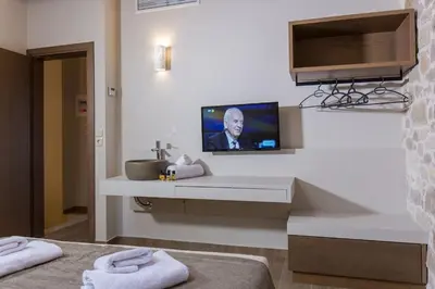 a bathroom with a sink and a tv on a wall at Kamartsos Villa 3 in Áyios Yeóryios