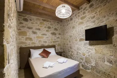 a bedroom with a bed and a tv in a stone wall at Kamartos Villa 1 in Áyios Yeóryios
