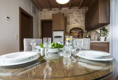 a dining room table with plates and glasses on it at Kamartos Villa 1 in Áyios Yeóryios