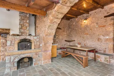a stone walled room with a table and a fireplace at ARADENA TRADITIONAL House 3 in Arádhaina