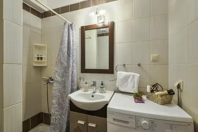 a white bathroom with a sink and a mirror at Lazaretta studio in Chania Town