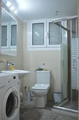 a bathroom with a toilet and a sink and a washing machine at Botonis Bright Spacious Apartment in Chania Town