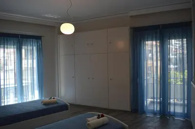 a bedroom with a bed and two large windows at Botonis Bright Spacious Apartment in Chania Town