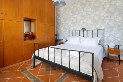 a bedroom with a bed with white sheets and a wall at Villa Elihrisos in Chorafakia