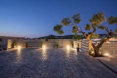 a patio with a fence and a tree at night at B&M HOUSE,SIRILI,PLATANIAS in Metókhion Sirilíou