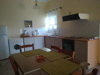 a kitchen with a table and a kitchen with a stove and refrigerator at Paleochora Elizabeth Apartments in Palaiochóra