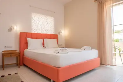 an orange bed in a room with a window at Nikos Rooms in Palaiochóra