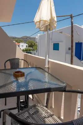 a table and chairs on a balcony with an umbrella at Nikos Rooms in Palaiochóra